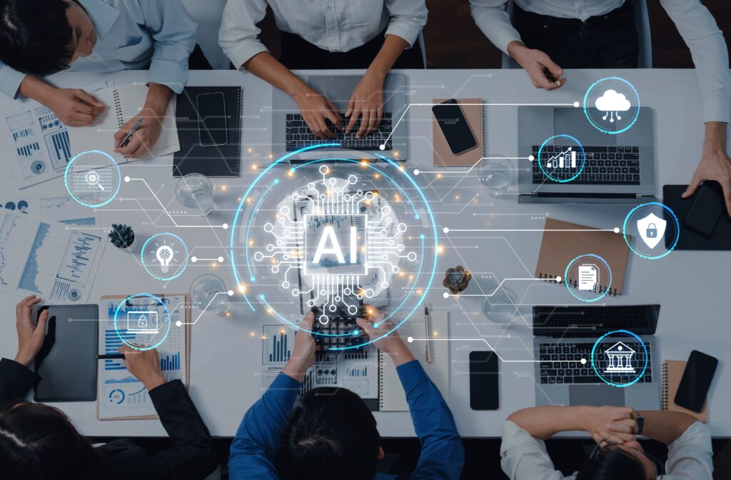 Top-down view of a diverse team around a table, using laptops with charts and notebooks, overlaid by AI graphics.